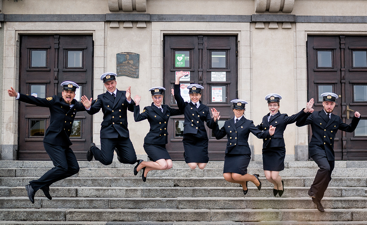 Studenci UMG przed frontonem budynku zeskakujący ze schodów