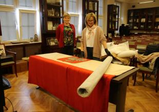 Konserwator z warszawskiej pracowni dokonuje oględzin i oceny stanu przedwojennej bandery z \"Daru Pomorza\"