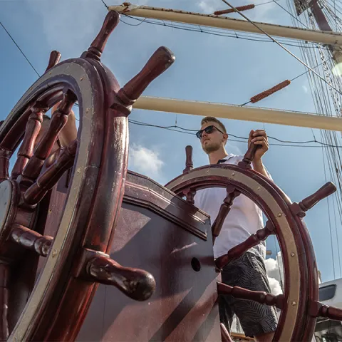 Student przy kole sterowym Daru Młodzieży